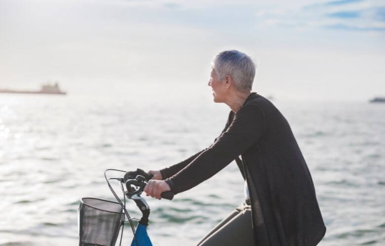 elderly woman biking close to sea side